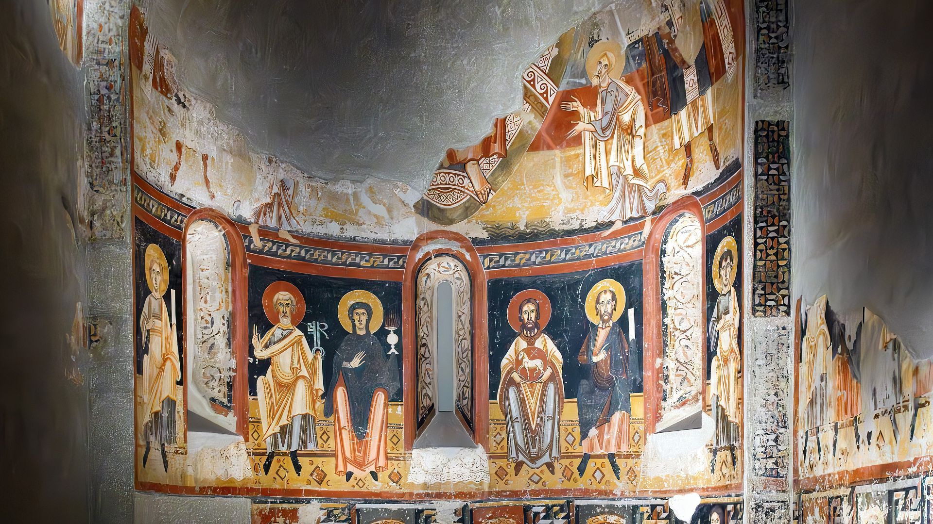 una antigua iglesia de piedra con una cruz en el techo está en medio de un campo verde .