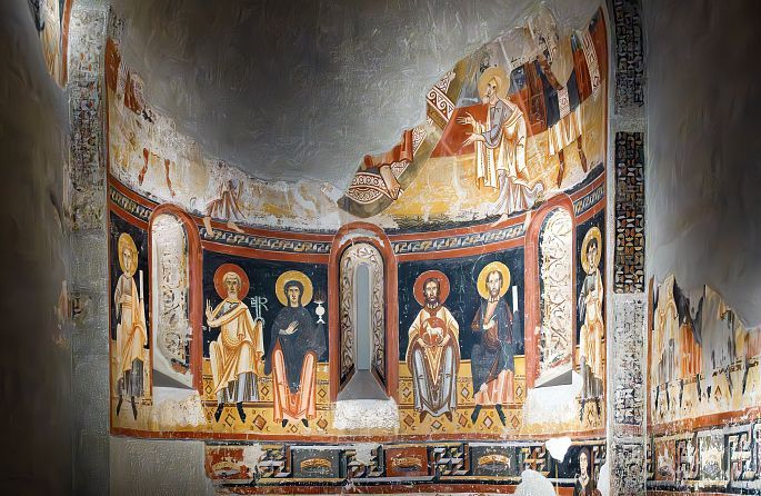 une vieille église en pierre avec une croix sur le toit se dresse au milieu d'un champ vert.