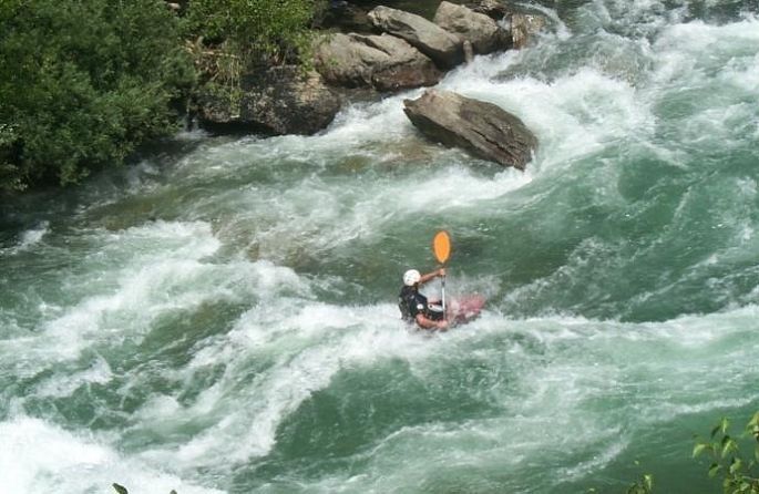 un homme dans un kayak sur une rivière avec une pagaie orange