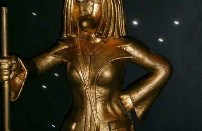 une statue d'une sorcière dorée avec un chapeau et un bâton