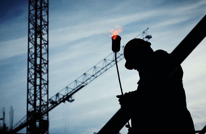 a silhouette of a construction worker holding a flame in his hand