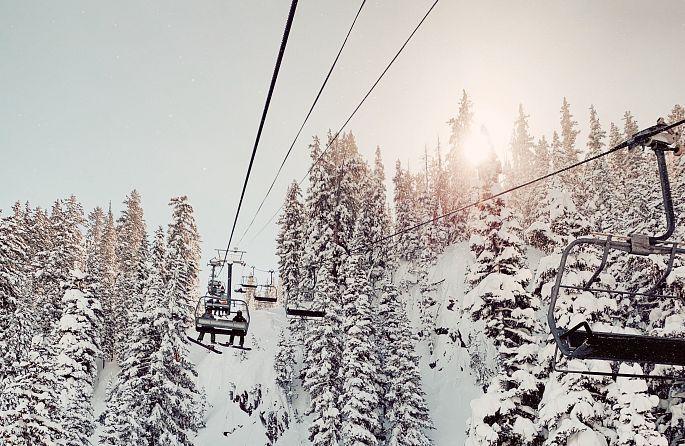 Un téléphérique emmène les skieurs à travers une forêt enneigée