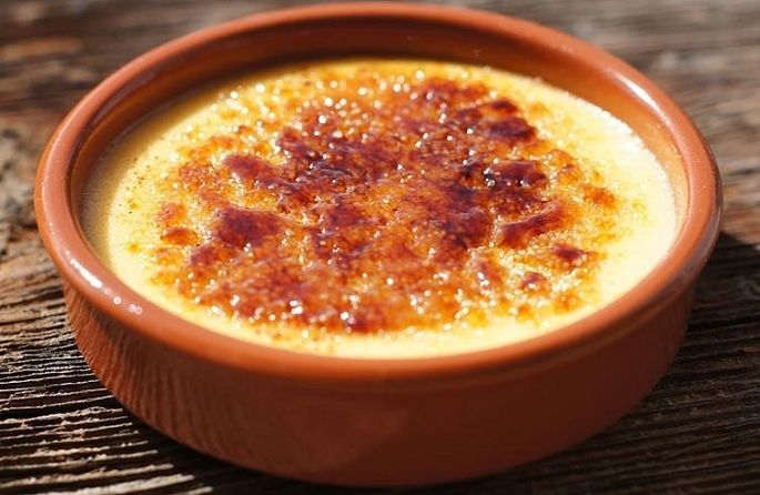 un bol en céramique rempli de crème brûlée sur une table en bois