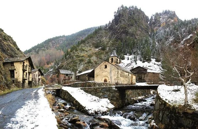 un village dans les montagnes avec une rivière et une église