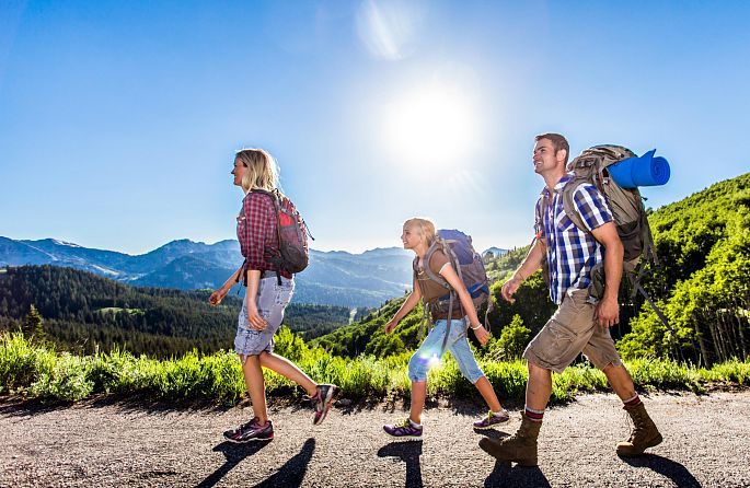 Une famille avec des sacs à dos marche le long d'un sentier vers les montagnes