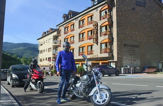 un homme debout à côté d'une moto devant un hôtel